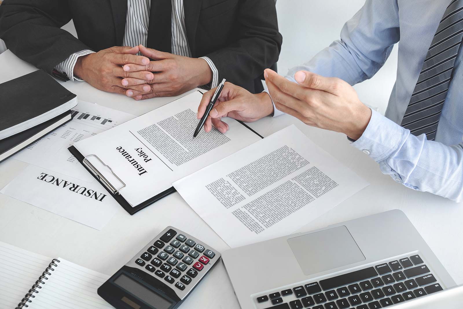Corretor de seguros explicando apólice para cliente em reunião de escritório
